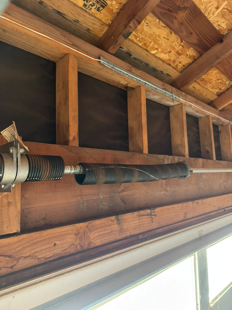 Torsion spring pair mounted above a wood-framed garage door opening in Salinas