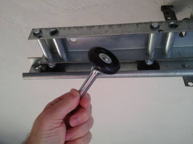 New garage door roller held against the top roller bracket during replacement