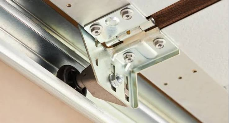 Close-up of a garage door hinge and roller seated inside the track between panels