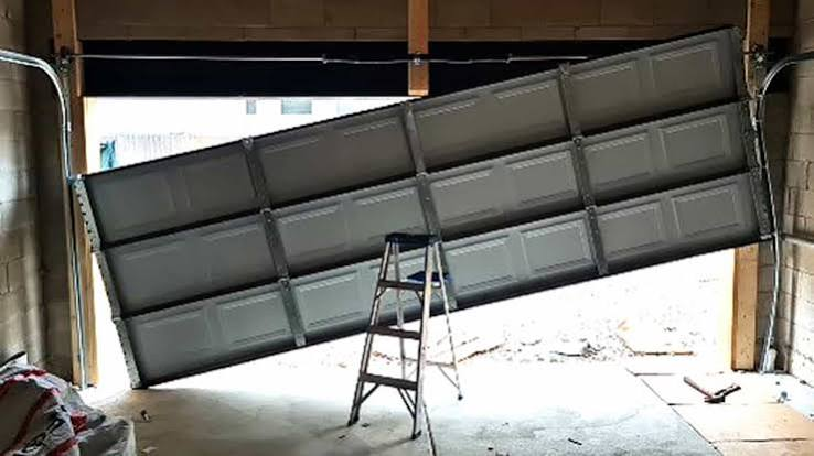 Sectional garage door that has come off its tracks, tilted inside the garage
