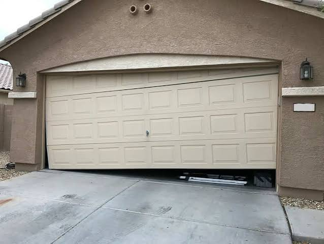 Garage door jammed at an angle in its opening, leaving a gap at the bottom
