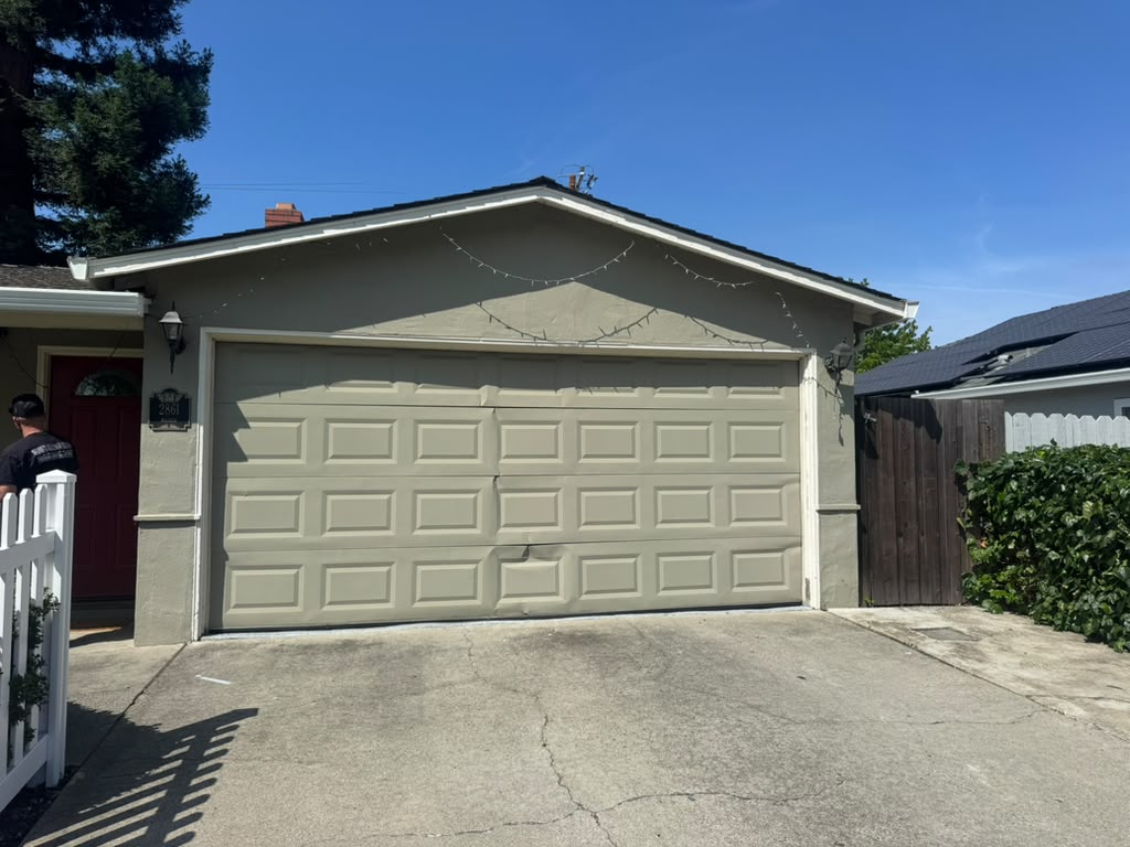 Cracked and dented garage door panel on a home before replacement