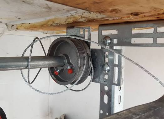Garage door lifting cable that has come off the torsion drum and tangled around the shaft