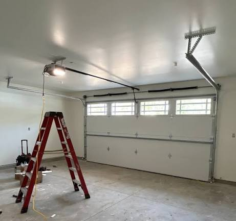 Garage interior with torsion springs, tracks, opener and ladder during an installation service