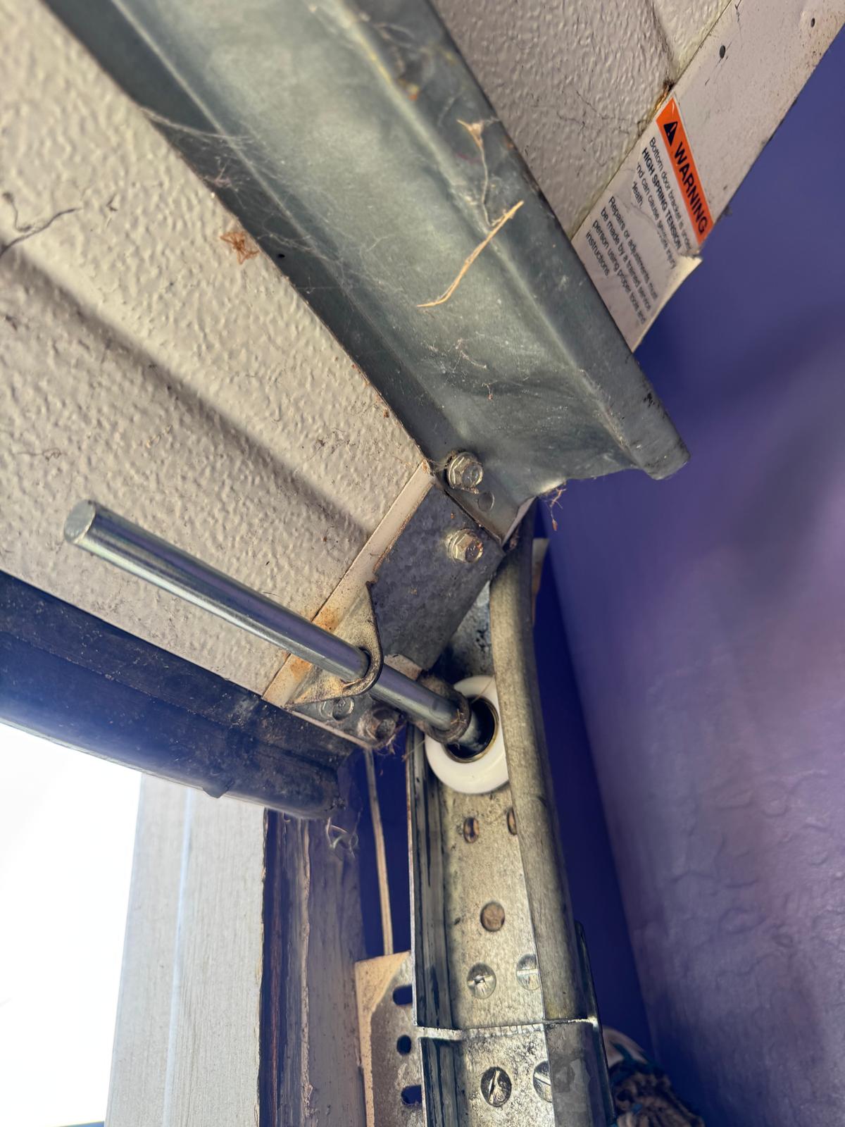 Garage door roller and vertical track corner with bracket hardware and warning label