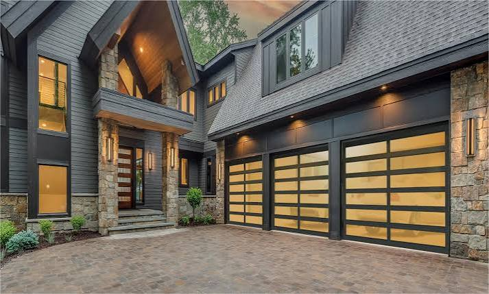 Modern frosted-glass garage doors with dark frames installed on a luxury home