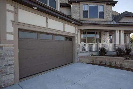 Newly installed modern garage door with horizontal windows on a multi-story home